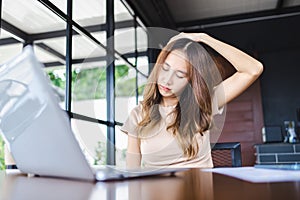 Young businesswoman stretch neck after working on computer laptop for a long time. Office syndrome concept