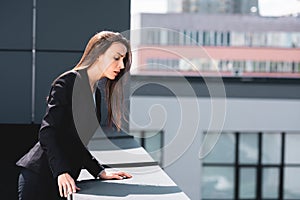 young businesswoman, suffering from acrophobia, looking down rooftop.