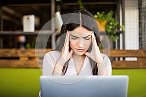 Young businesswoman suffering from headache in front of laptop at office