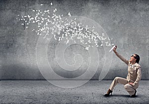 Young businesswoman with suitcase using spray