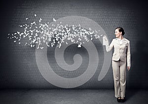 Young businesswoman with suitcase using spray