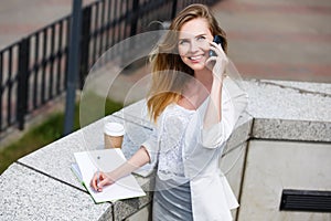 Young businesswoman talking on cellphone while walking outdoor