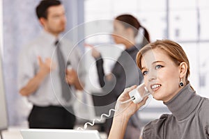 Young businesswoman talking on phone in office