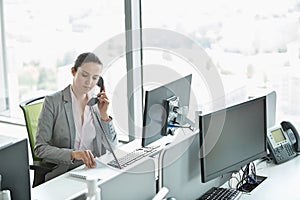 Young businesswoman talking on telephone in office