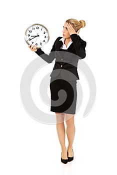 Young businesswoman terrified looks at the clock