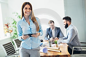 Young businesswoman using digital tablet while colleague in background