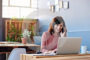 Young businesswoman using a laptop and talking on her cellphone