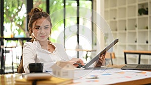 Young businesswoman using laptop and working with financial document at contemporary workplace