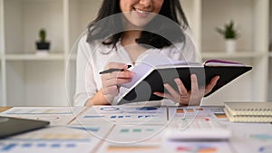 Young businesswoman using laptop and working with financial document at contemporary workplace