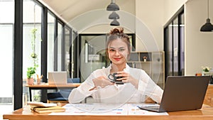 Young businesswoman using laptop and working with financial document at contemporary workplace