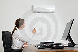 Businesswoman Using Remote Control In Front Of Air Conditioner