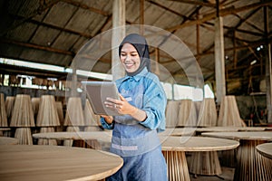young businesswoman in veil using a tablet in wood craft shop