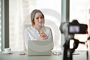 Young businesswoman vlogger recording vlog talking to camera in photo