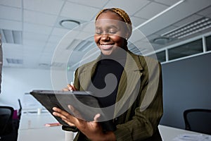 Young businesswoman in businesswear smiling while using digital tablet and digitized pen in office photo