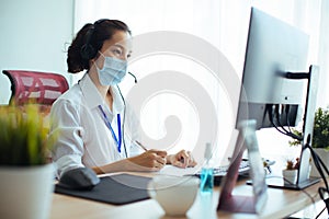 Young businesswoman wearing face mask while working on a computer in the office