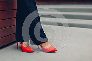 Young businesswoman wearing red high heeled shoes. Stylish classic pumps. Closeup of female legs.