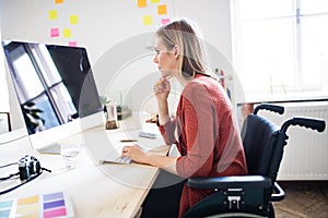 Businesswoman in wheelchair at the desk in her office.