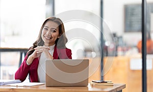 Young businesswoman working at her laptop and going over paperwork while sitting at a desk in an office