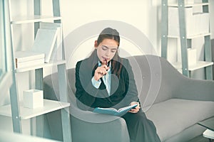 Young businesswoman working on laptop with too much work in office. Secretary girl notes in notepad.