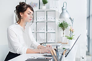 Young businesswoman working in office, typing, using computer. Concentrated woman searching information online