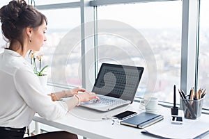 Young businesswoman working in office, typing, using computer. Concentrated woman searching information online, rear