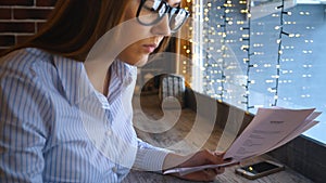 A young businesswoman works in a cafe and looks at the documents