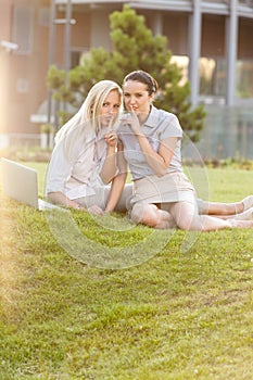 Young businesswomen gesturing silence in office lawn