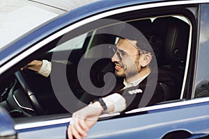 Young bussinesman in suit and black glasses driving his car. Bussines look. Test drive of the new car