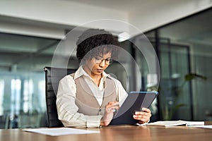 Young busy African business woman manager using tablet working in office.