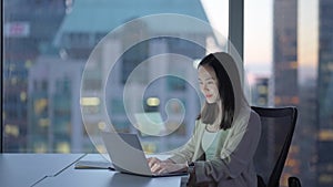 Young busy Asian business woman executive working on laptop in corporate office.