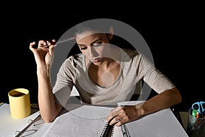 Young busy beautiful Spanish girl studying at home late night looking preparing exam concentrated