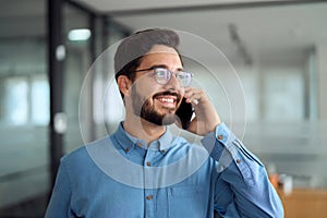 Young busy latin businessman talking on the phone in office.