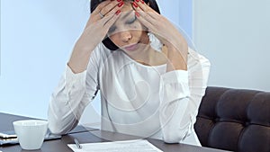 Young busy woman feeling not well but continuing signing papers photo