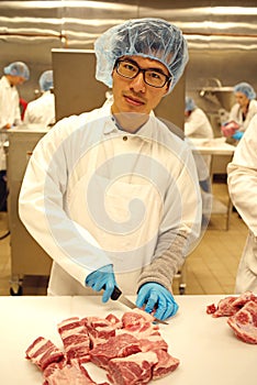 A young butcher cutting meat