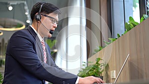 Young call center operator taking a call at the help desk. Smiling customer support operator at work. Businessman using a headset