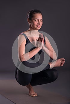 Young calm beautiful woman of the brunette with long hair wearing black sportswear in yoga pose