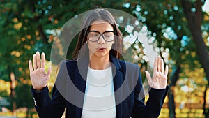 Young calm businesswoman relaxing, meditating at green park. Girl refuses stress and takes situation, calms down, breathes deeply