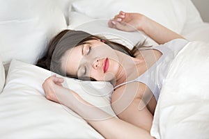 Young woman relaxing sleeping in cozy white bed