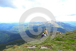 Young calm female tourist wearing yellow jacket sitting in Appenine mountains.