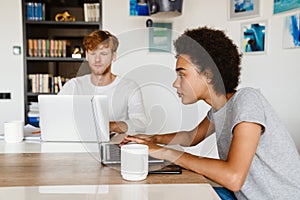 Young calm redhead man and beauitiful african woman working together