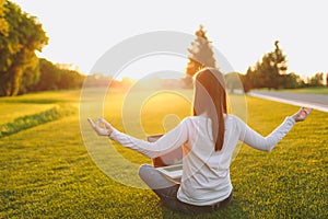 Young calm student female in casual clothes. Woman sitting, relaxing, hands in yoga gesture. Laptop pc computer on green