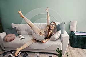 Young calm woman with laptop relaxing sit on comfortable sofa in at home after work,
