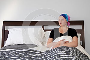 Portrait of a young cancer patient resting in bed looking out window