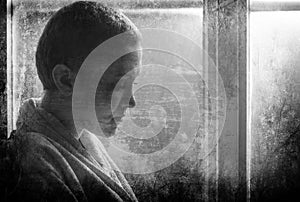 Young cancer patient standing in front of hospital window