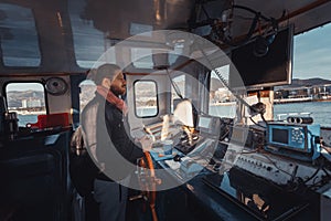 Young Capitan With Beard Stands At The Helm And Controls The Ship, View From Inside Captain`s Cabin