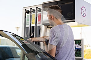 Young car driver man in casual on fuel station near gas pump