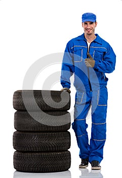 Young car mechanic with pile car tires