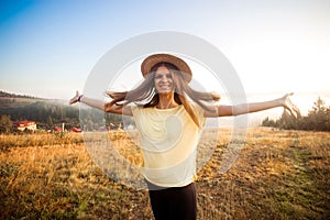 Young carefree woman enjoying nature and sunlight in straw hat