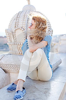 Young carefree woman sitting at monument