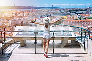 Young carefree woman tourist in sun hat with open arms enjoying view of Lisbon city from viewpoint. Travel and vacation